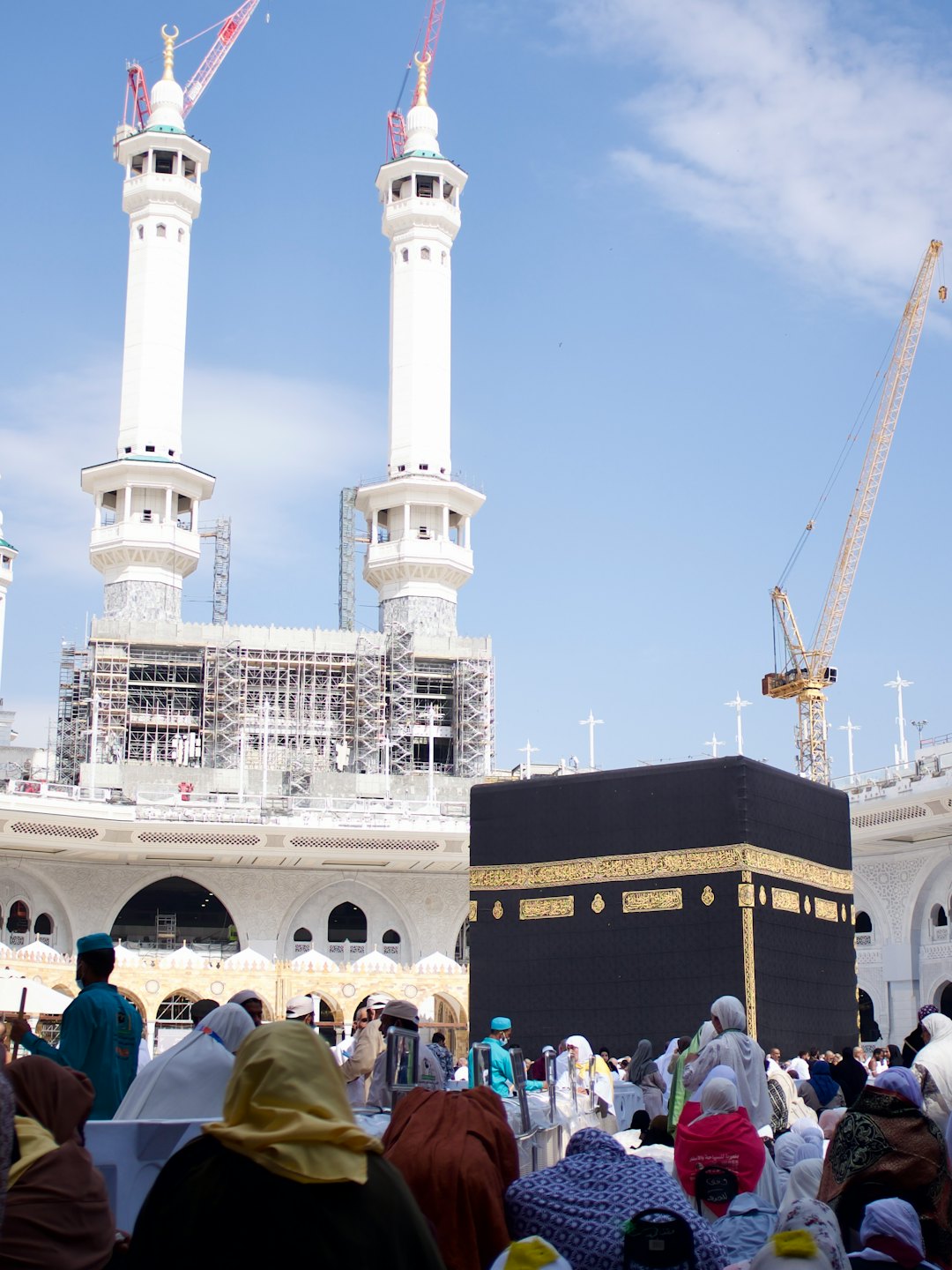 Des pèlerins se rassemblent autour de la Kaaba près de grandes grues de construction.